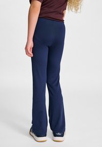Marina blå flarebyxor i stretchigt material, med elastisk midja och slät yta. Klares med marina blå sportskor.