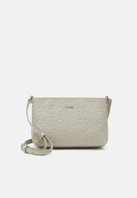 Světlý béžový crossbody batoh vyrobený z texturované umělé kůže, se vzorem vystouplého loga CK a odnímatelným popruhem.