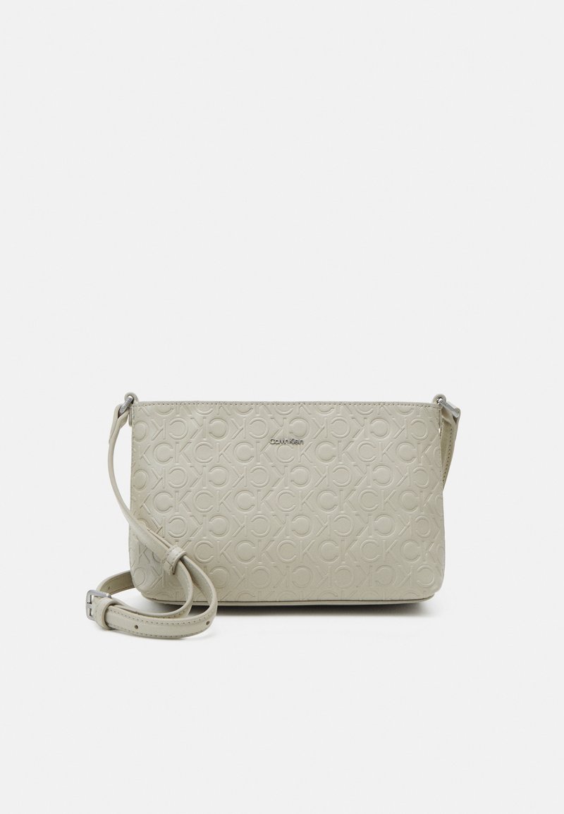 Světlý béžový crossbody batoh vyrobený z texturované umělé kůže, se vzorem vystouplého loga CK a odnímatelným popruhem.