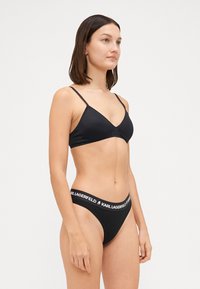 Set di bikini nero con top a triangolo a spalline sottili e slip a vita alta, realizzato in tessuto morbido con una fascia in vita con logo.