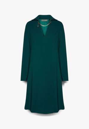 Vestido azul verdoso con cuello, mangas largas y escote en V. Presenta aberturas laterales y un acento decorativo de cadena en el escote. Textura suave.