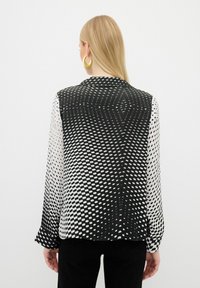 Black and white blouse with a gradient dot pattern, long sleeves, collar, and a smooth, lightweight texture.
