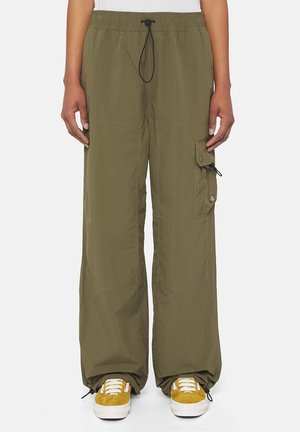 Adult wearing olive green wide-leg cargo pants with drawstrings at waist and ankles, paired with mustard yellow sneakers with white laces.