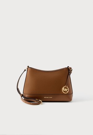 Καφέ δερμάτινη τσάντα ώμου Michael Kors με ρυθμιζόμενο λουρί και χρυσό μενταγιόν λογότυπο MK σε απλό φόντο.