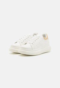 Bílé kožené tenisky s hladkým povrchem, zaoblenou špičkou, šněrováním a béžovým akcentem na patě. Tlustá gumová podrážka.