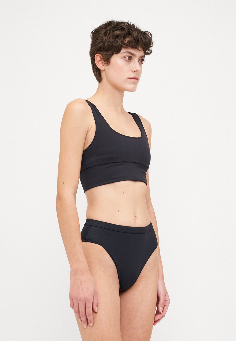 Melnas bikinis komplekts ar pieguļošu bralete topu ar platām siksnām un atbilstošām augstām biksītēm. Gluda, elastīga auduma bez rakstiem.