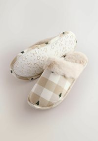 Beige checkered slippers with small green tree prints, fluffy lining, and star-and-moon patterned non-slip soles on a neutral background.
