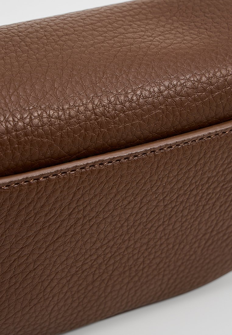 Bolso de cuero marrón con una superficie texturada, una forma limpia y un sutil detalle de costura a lo largo del borde.