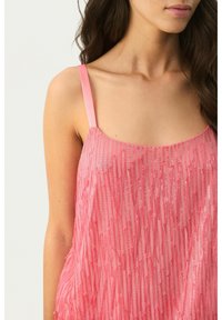 Pink tanktop med lige stropper, der har et tekstureret design med lodrette glitrende frynser for ekstra visuel interesse.