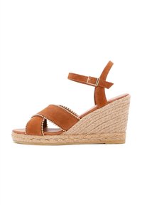 Bruine suède wedge sandaal met gevlochten jute zool, crisscross banden en decoratieve gouden kralen op een van de banden.