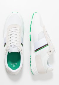 Weiße Mesh- und Wildledersneaker mit grünem Gummisohle, die ein mehrfarbiges Streifenmuster über dem Obermaterial und eine grüne Innenauskleidung aufweisen.