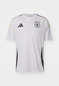 Camiseta de fútbol de manga corta blanca con detalles en negro, tres estrellas sobre un logo redondo y rayas de color en los hombros. Fabricada con material ligero.
