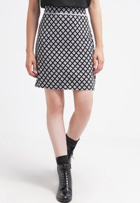 Mustat hame, jossa on valkoisia timantti kuvioita. Tiukka malli ja keskikorkea vyötärö. Yhdistetty mustiin nauhakengät nilkkoihin ja sukkiin.