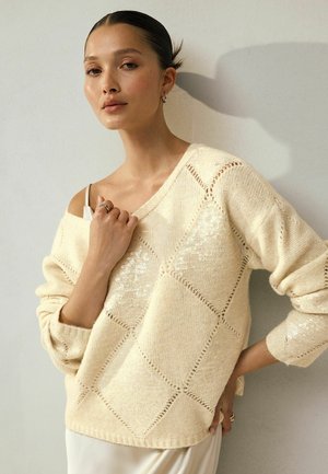 Helles beiges Strickpullover mit lockerer Passform, Rautenmuster und dezenten Pailletten. Verfügt über weite Ärmel und einen tiefen V-Ausschnitt.