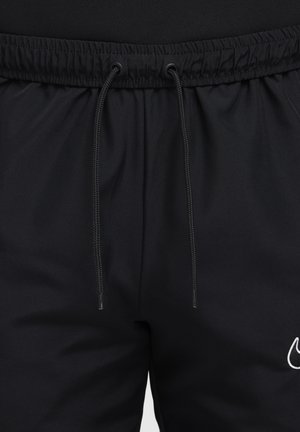Schwarze Sportshorts aus glattem Stoff mit einem elastischen Bund, der eine verstellbare Kordel hat, und einem weißen Logo-Akzent am Bein.
