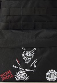 Fekete szövet táska hímzett foltokkal: démon koponya, kardok, "HELLFIRE FOREVER" felirattal és egy dobószám szimbólummal; vízszintes heveder pántokkal rendelkezik.