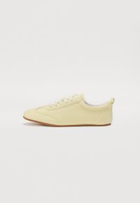 Sneaker giallo in pelle con tomaia testurizzata, chiusura con lacci e suola in gomma a contrasto. Foderato in morbido tessuto e dotato di un inserto per il tallone.