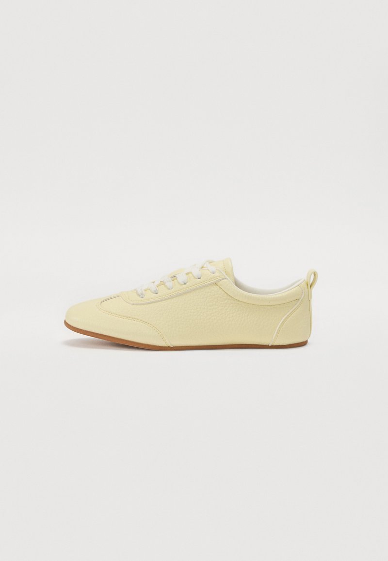 Sneaker giallo in pelle con tomaia testurizzata, chiusura con lacci e suola in gomma a contrasto. Foderato in morbido tessuto e dotato di un inserto per il tallone.