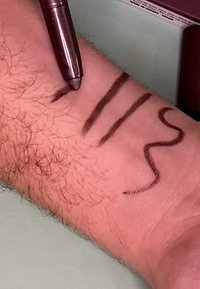 Des lignes réalisées au marqueur marron sur un avant-bras, présentant trois motifs distincts : une ligne droite, une ligne ondulée et une ligne courbée sur une peau claire.