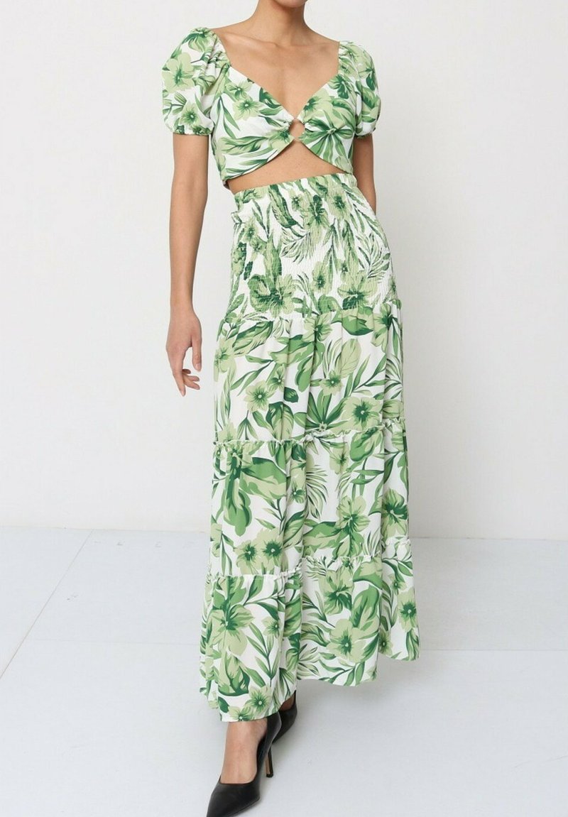 Ensemble floral vert en deux pièces comprenant un haut court avec des manches bouffantes et une jupe maxi à volants taille haute. Tissu texturé, finition lisse.