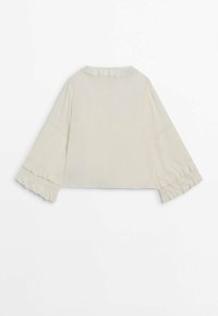 Blouse crème à manches longues avec manches larges et détails volantés sur les poignets et le col, vue de dos.