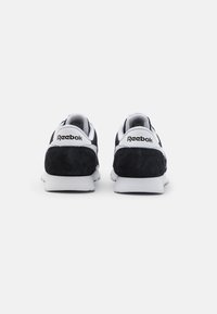 Černobílé sportovní boty se semišovými akcenty na patě a bílými gumovými podrážkami. Mají logo Reebok na patě a klasický design.