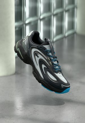 Black and gray athletic shoe with mesh upper, blue laces, and a turquoise sole, featuring wavy design patterns and reflective accents.