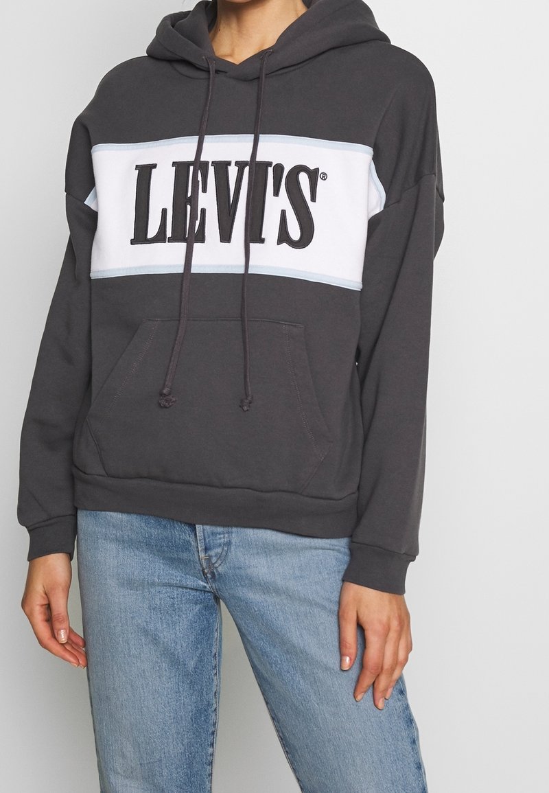Felpa grigia con cappuccio e striscia bianca e azzurra chiara con logo "LEVI'S". Include tasca frontale e polsini a costine. Materiale in misto cotone.