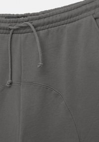 Grå sweatpants med dragsko i midjan, slät tygtextur och sidofickor. Designen är enkel med sömnadsdetaljer.