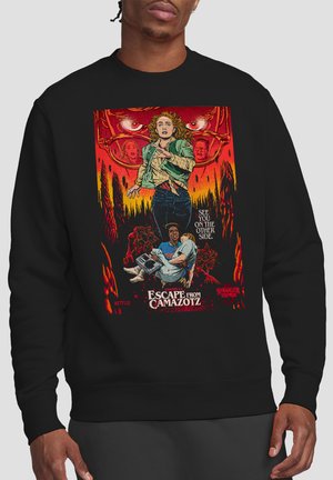 Frau läuft mit besorgtem Gesichtsausdruck, Mann trägt Kind darunter, rote Augen und Gesichter im Hintergrund, Schriftzug "Escape from Camazotz" auf schwarzem Sweatshirt.