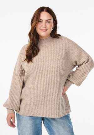 Beige ribbed sweater with a high neck, relaxed fit, and balloon sleeves. Worn with light blue jeans. Soft texture and subtle design details.