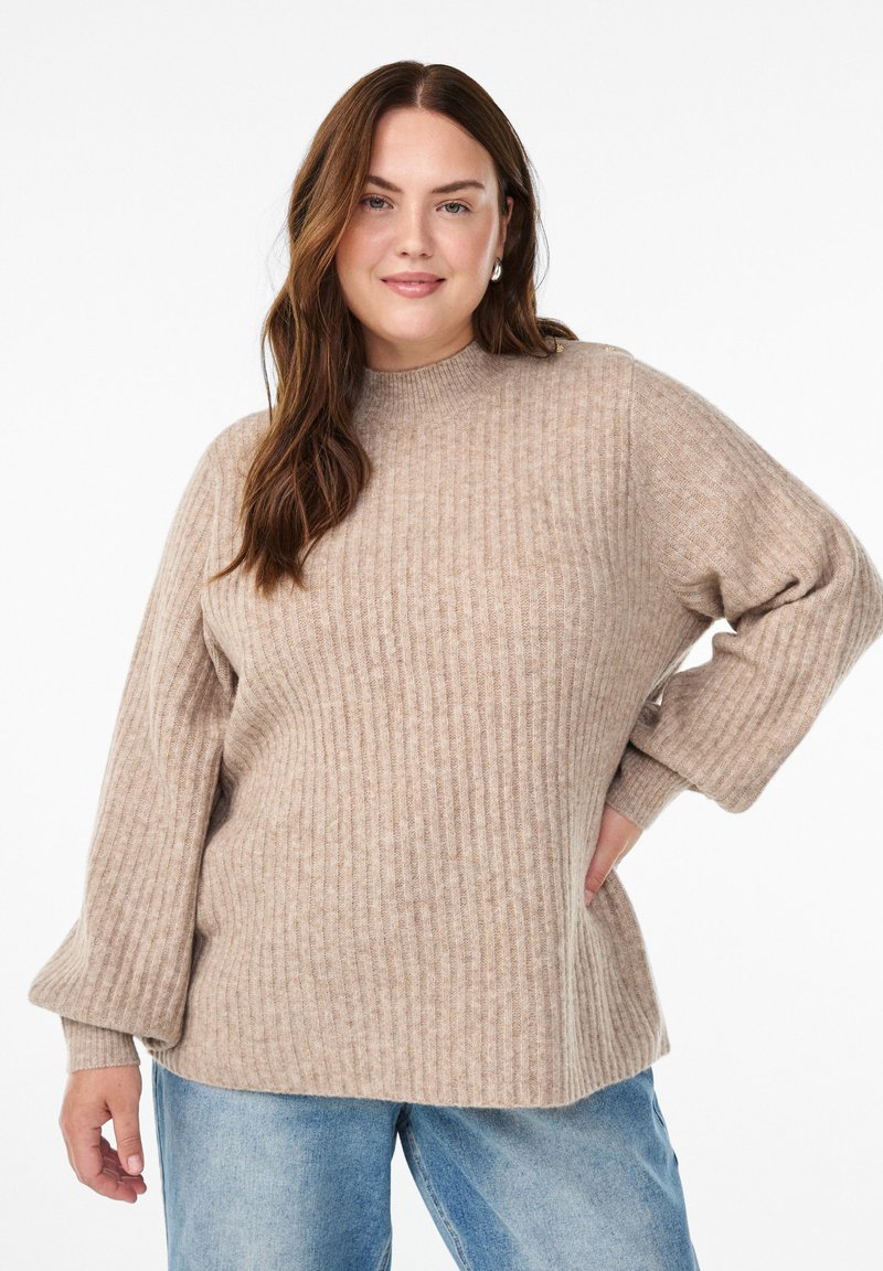 Beige Ripp-Strickpullover mit hohem Hals, lockerer Passform und Ballonärmeln. Trägt man zu hellblauen Jeans. Weiche Textur und subtile Designdetails.