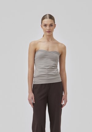 Top sans bretelles gris en tissu lisse, doté d'un design ajusté avec un léger plissage à la taille. Associé à un pantalon marron foncé.
