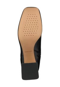 Suola di scarpa in pelle nera con superficie texturizzata, caratterizzata da perforazioni e un sottopiede liscio color tan. Logo "GEOX" stampato sulla superficie.
