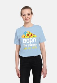 Světle modré tričko s krátkým rukávem s karikaturou pizzy a textem „NAROZEN k spánku a jídlu PIZZA“ v bílé a žluté barvě.