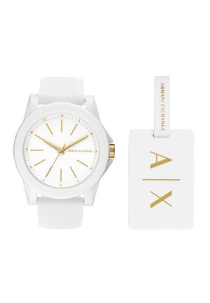 Montre-bracelet blanche Armani Exchange avec des accents dorés et une étiquette blanche assortie affichant le logo "A|X" en lettres dorées.