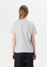 T-shirt en coton gris à manches courtes, col rond et coupe décontractée, avec une texture lisse et sans graphiques ni motifs visibles.