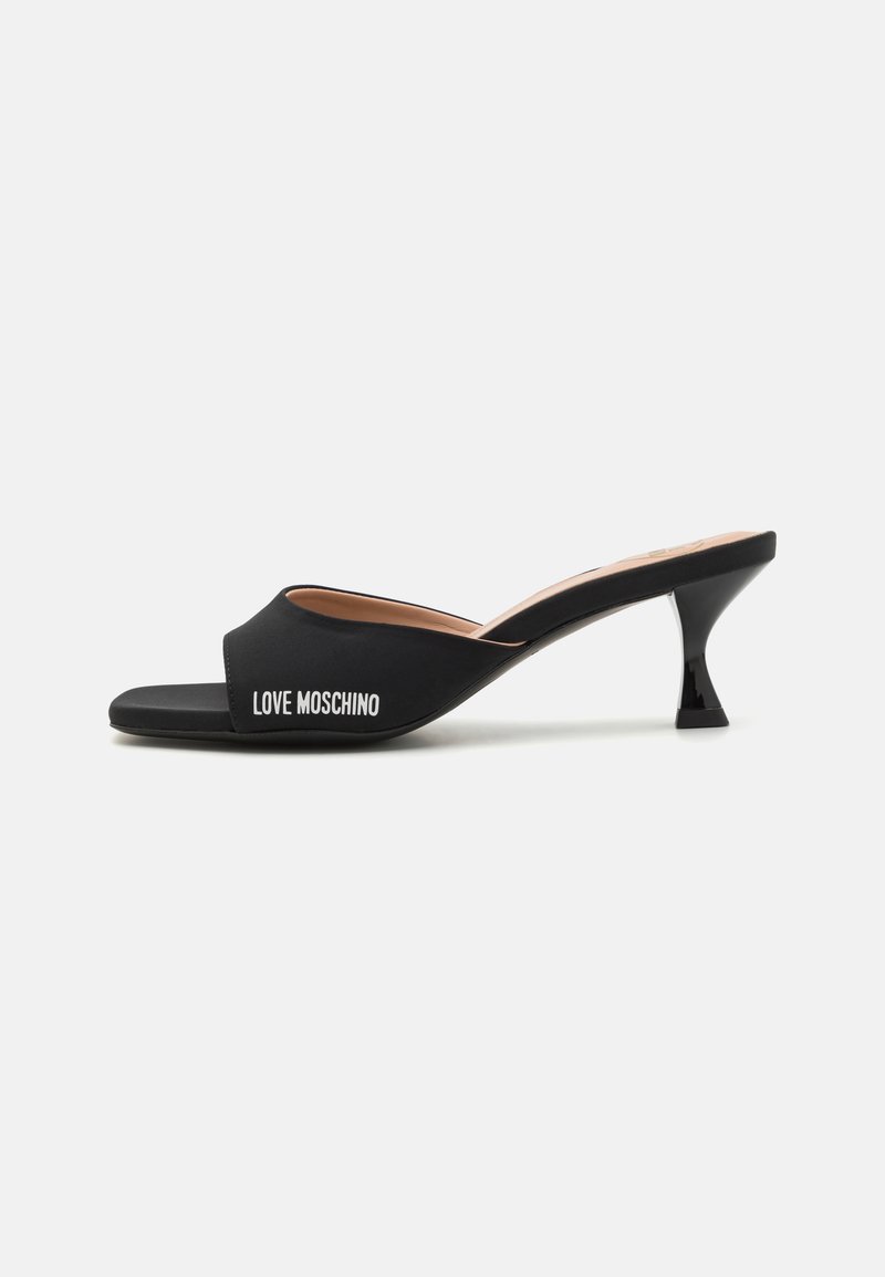Fekete, nyitott orrú mules vékony, háromszögletű sarokkal. Simaságot sugalló felsőrésszel rendelkezik, oldalán fehér betűkkel a "LOVE MOSCHINO" felirattal.
