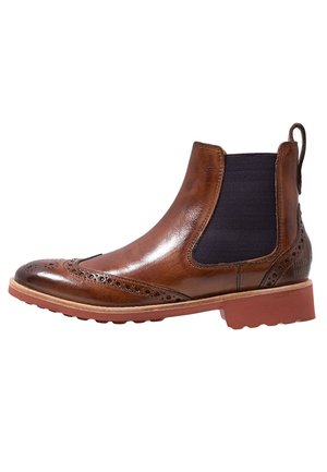 Brun læder Chelsea-støvle med brogue-detaljer, sort elastisk sidepanel og tyk gummisål med trækflige bagpå.