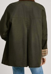 Mörkgrön kappa med krage, utrustad med en slits bak och rutmönstrade detaljer på ärmarna. Tillverkad av slätt material, avslappnad design.