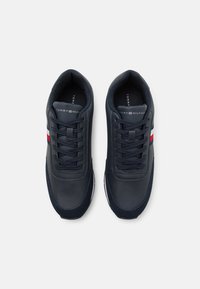 Sneaker in pelle blu con finitura liscia, dotati di una linguetta in tessuto testurizzato, lacci neri e accenti a strisce rosse e bianche.