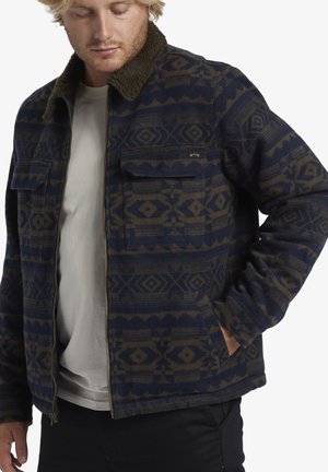 Bluish jacket with a geometric pattern in dark brown. Features a zip front, two chest pockets, and a contrasting fuzzy collar.