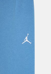 Gaiši zili kokvilnas sporta bikses ar balto izšūto Jumpman logo zem kreisā pēdas, ar mīkstu tekstūru un brīvu piegriezumu.