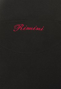 Tissu noir côtelé avec "Rimini" en cursive rouge brodée, montrant la texture et les détails de la couture.