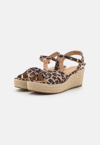 Sandales compensées à imprimé léopard avec des brides croisées, plateforme en jute naturel et design à bout ouvert. Palette de couleurs marron clair et noir.
