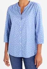 Chemise bleu clair à manches trois-quarts, avec un col frais, ornée d'un motif de feuilles blanches, fabriquée en un doux mélange de coton.
