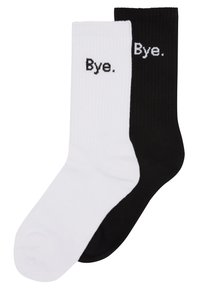 Calzini in cotone a lista, uno nero e uno bianco, con una texture a costine e la parola "Bye." ricamata in nero sul calzino bianco e in bianco su quello nero.