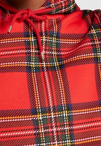 Felpa con cappuccio a motivi scozzesi rossi con cordoncino regolabile. Realizzata in un tessuto misto cotone, presenta un motivo a quadri distintivo nei colori rosso, verde e giallo.