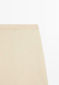 Gestrickter beiger Rock mit einem gerippten Bund. Weiche Textur und glatte Oberfläche, mit schlichtem, geradem Design ohne Muster oder Akzente.