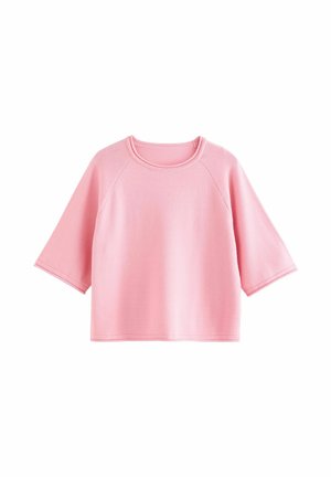 Roosa lühikeste varrukatega top, tehtud pehmest kangast. Omab ümarat kaelust ja raglaanvarrukaid. Lihtne, lahtise lõikega disain ilma lisamustriteta.